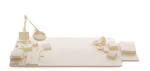 Precise three-dimensional paper reconstruction of a workspace by Herbert Stattler, showing desk objects as monochromatic white paper models based on original pencil drawings.